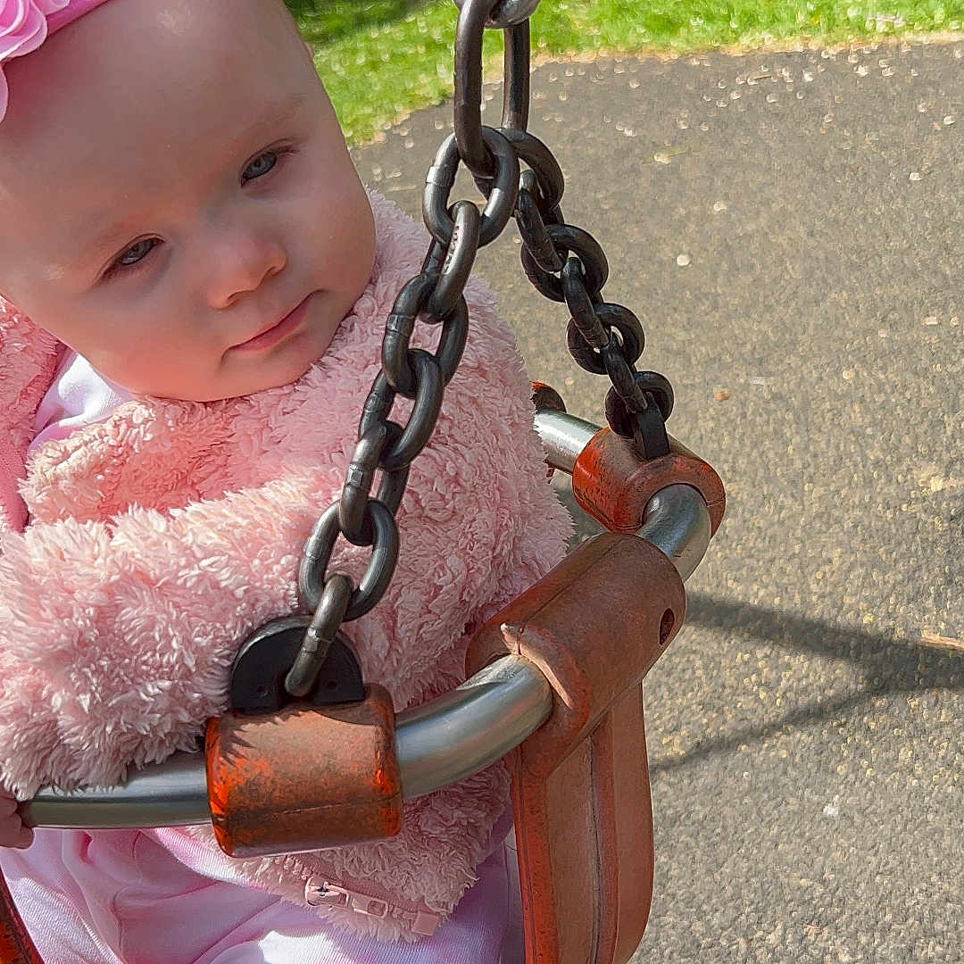 Penelope-Rose is registered to the contest to win money with this photo: baby, chain, clothing, dress, face, fence, grass, hat, head, nature, outdoorplayarea, outdoors, park, person, photography, plant, playarea, portrait, swing, toy