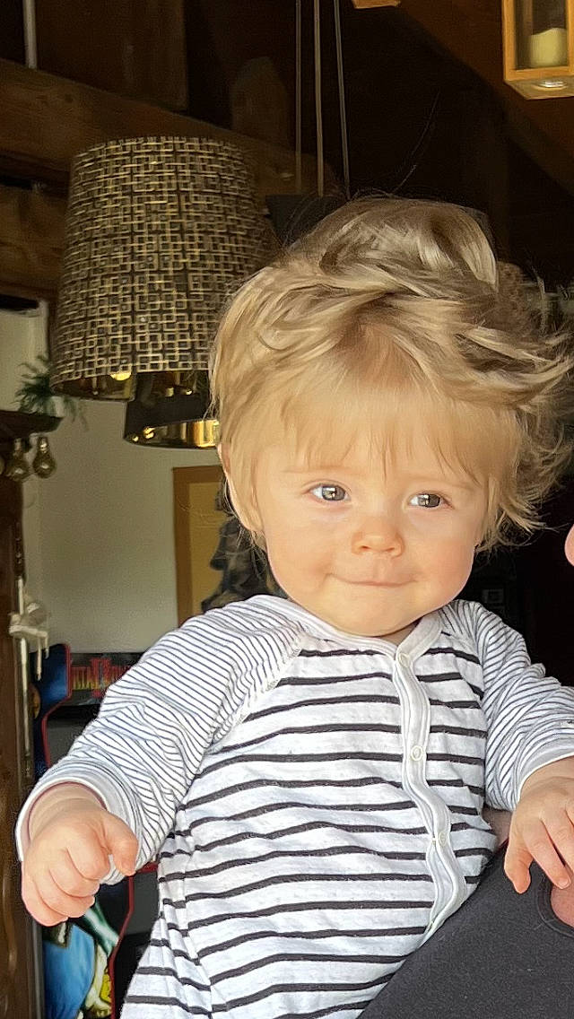 Marius a rejoint le concours — aidez-le/la à gagner de superbes lots ! arm, baby_toddler_clothing, blond, cheek, child, chin, curtain, eye, fun, happy, head, iris, lamp, person, sitting, sleeve, smile, standing, t_shirt, toddler