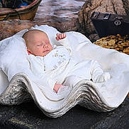 Theo is registered to the contest to win money with this photo: baby, sleeping, infant, clam_shell, treasure_chest, gold_coins, white_clothing, cute, peaceful, soft_fabric, decor, props, portrait, newborn, resting, indoors, creative_setup, baby_pose, artistic, fantasy_theme