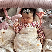 Amelia joined the competition — help win amazing prizes! baby, sleeping, blanket, onesie, plush_toys, baby_gym, bow, hair_accessory, infant, cozy, soft_toys, pink, white, cute, peaceful, child, indoor, resting, newborn, comfort