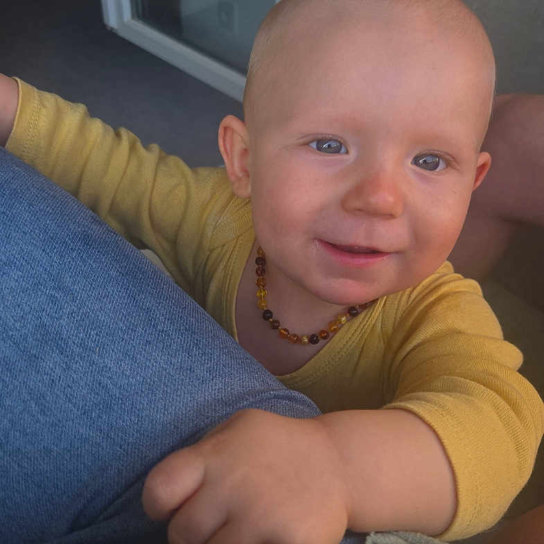 Djino a rejoint le concours — aidez-le/la à gagner de superbes lots ! amber_necklace, baby, child, closeup, curious, face, floor, glass_door, hand, happy, home, indoor, jeans, knitted_sweater, person, portrait, skin, smiling, window, yellow_shirt