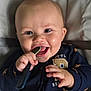 Hudson is registered to the contest to win money with this photo: baby, smiling, spoon, hand, face, clothing, blue, star_pattern, infant, cute, happy, portrait, close_up, child, chewing, sitting, indoors, skin, eyes, mouth