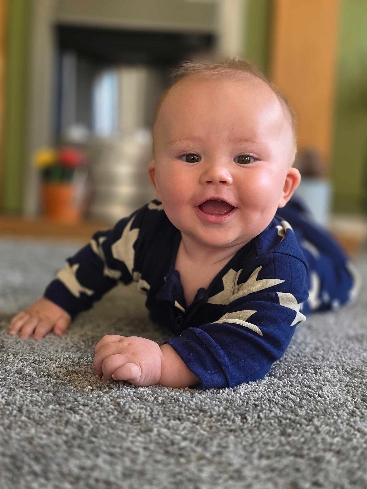 Hudson is registered to the contest to win money with this photo: baby, smiling, carpet, blue_clothing, indoor, child, happy, face, hands, crawling, infant, cute, chubby_cheeks, home, floor, person, portrait, young, cozy, patterned_clothing