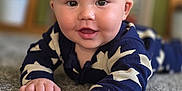 Hudson is registered to the contest to win money with this photo: baby, infant, child, carpet, lying_down, blue_clothing, stars_pattern, hand, face, smiling, indoor, soft_texture, cute, young, portrait, skin, eyes, happy, reaching, closeup