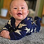 Hudson is registered to the contest to win money with this photo: baby, infant, smiling, face, blue_onesie, star_pattern, carpet, indoors, happy, child, cute, portrait, lying_down, hands, skin, head, eyes, mouth, cheeks, soft_focus