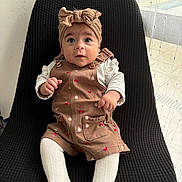 Cléa participe au concours pour gagner de l'argent avec cette photo : baby, infant, child, sitting, headband, romper, white_tights, chair, black_chair, curious_eyes, indoors, natural_light, window, sheer_curtains, cute, clothing, portrait, small_hands, expression, comfortable