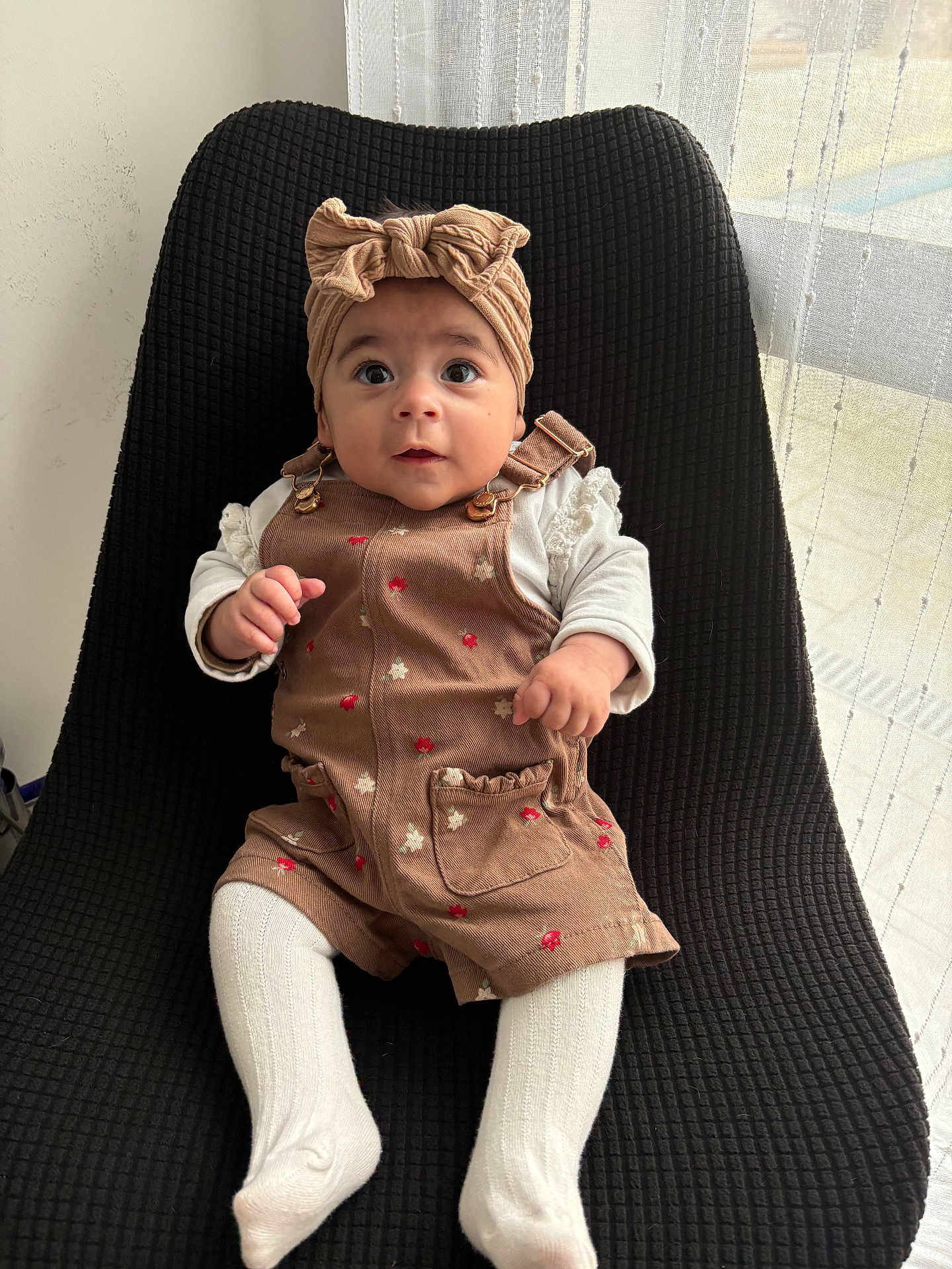 Cléa participe au concours pour gagner de l'argent avec cette photo : baby, infant, child, sitting, headband, romper, white_tights, chair, black_chair, curious_eyes, indoors, natural_light, window, sheer_curtains, cute, clothing, portrait, small_hands, expression, comfortable
