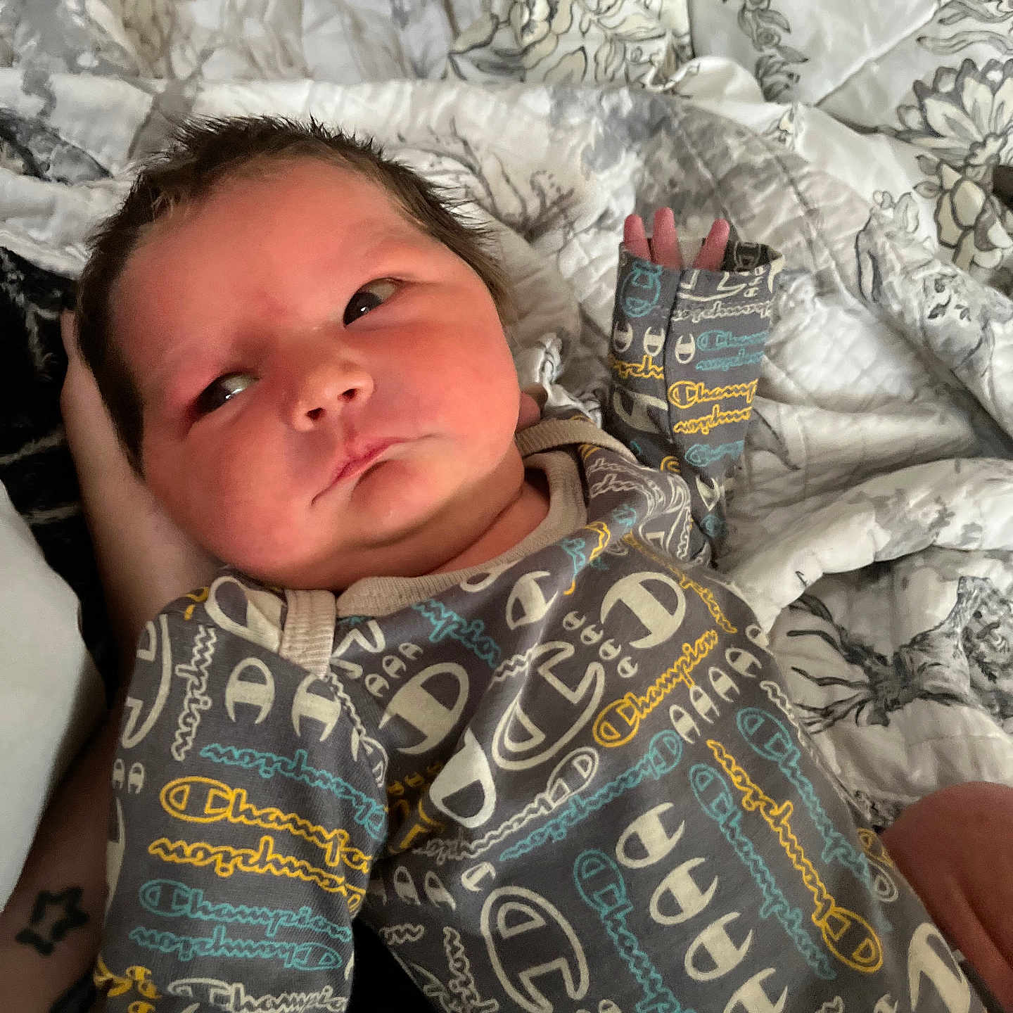 Liam joined the competition — help win amazing prizes! baby, bed, blanket, clothing, comfort, cute, face, hand, indoor, infant, newborn, onesie, pattern, person, portrait, quilt, resting, skin, sleepwear, young