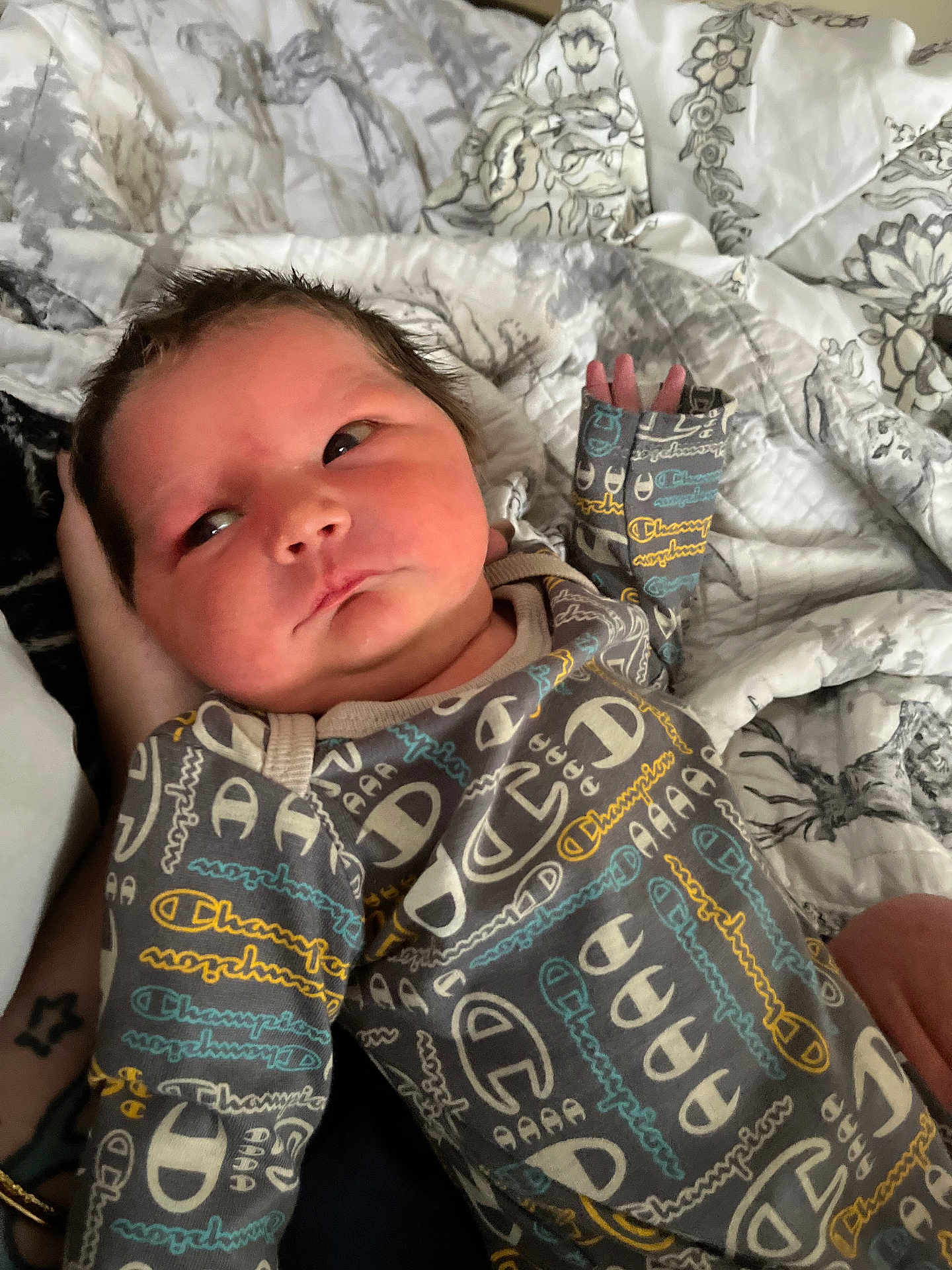 Liam joined the competition — help win amazing prizes! newborn, baby, infant, clothing, onesie, pattern, hand, quilt, blanket, bed, face, person, sleepwear, skin, cute, young, portrait, indoor, resting, comfort