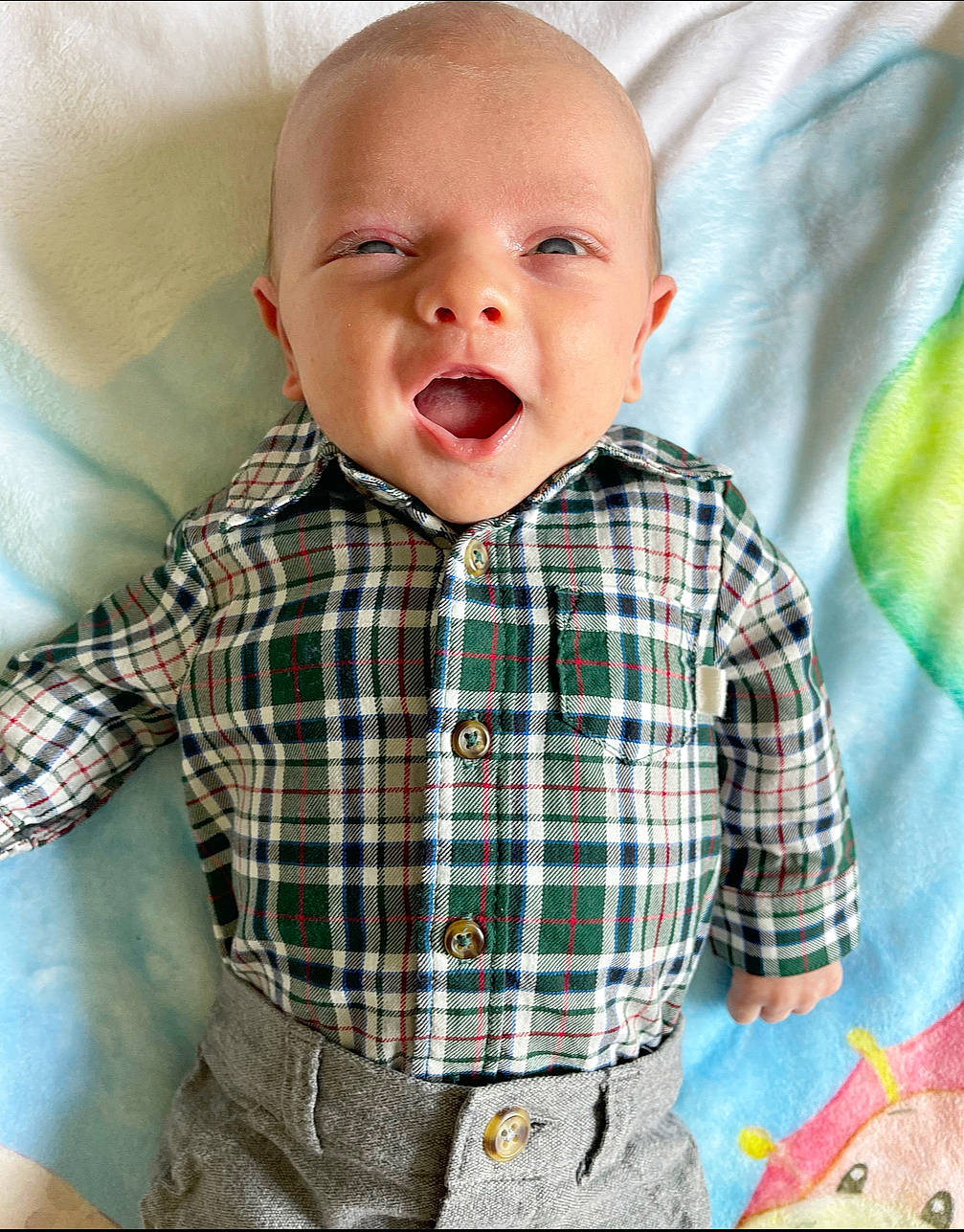 Case is registered to the contest to win money with this photo: baby, baby_toddler_clothing, bedding, child, collar, comfort, dress_shirt, fun, happy, linens, pattern, person, plaid, product, sitting, sleeve, smile, t_shirt, tartan, textile