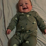 Wyatt joined the competition — help win amazing prizes! baby, smiling, onesie, green_clothing, animal_print, bed, sheet, lying_down, happy, infant, child, cute, soft_lighting, indoor, person, footwear, sleepwear, small_child, cozy, portrait