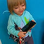 black_shoes, blue_door, cardigan, casual_clothing, child, floor_tiles, footwear, full_body, girl, happy, indoors, person, phone, playful, scarf, short_hair, smiling, standing, wall, young_child