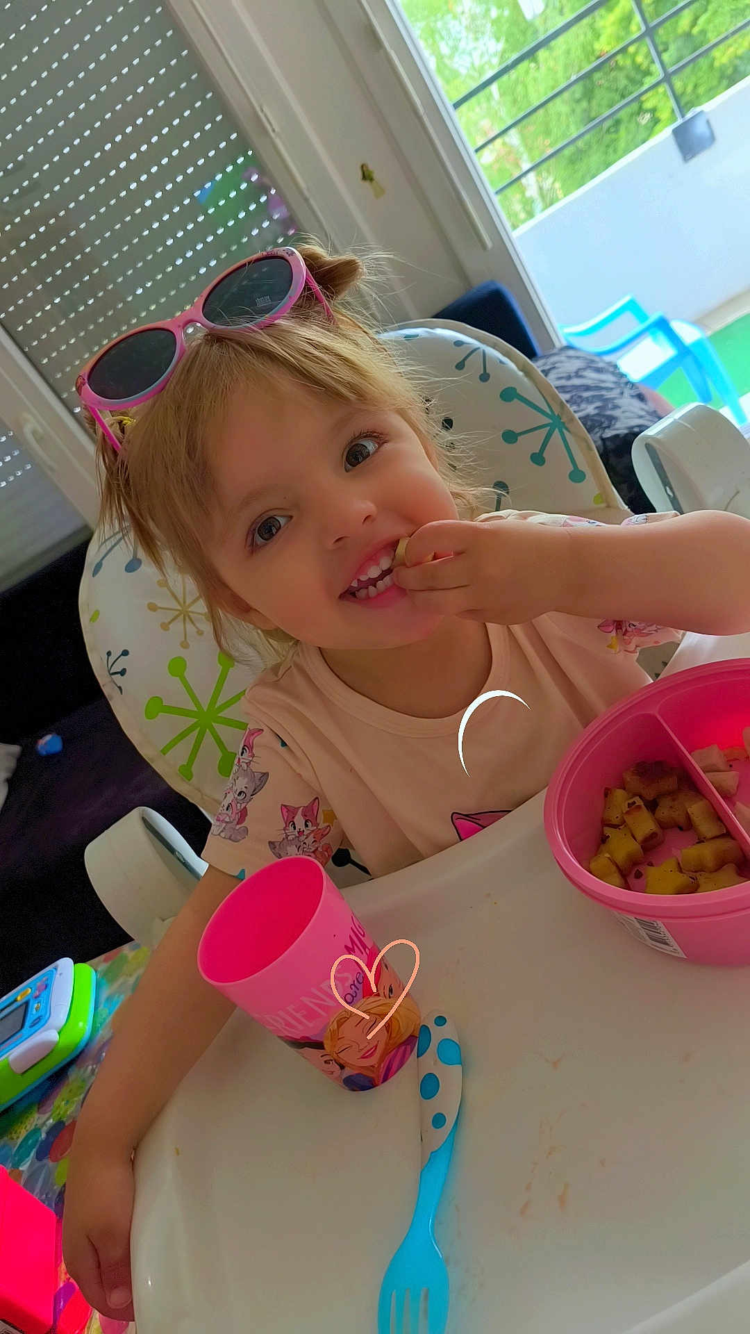 Mélody a rejoint le concours — aidez-le/la à gagner de superbes lots ! child, toddler, high_chair, sunglasses, pink, food, snack, cup, bowl, fork, indoor, window, smiling, happy, table, plastic_utensil, colorful, hair, person, eating
