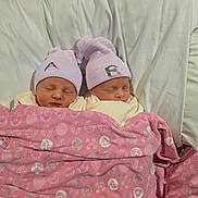 Catalina is registered to the contest to win money with this photo: newborn, twins, babies, sleeping, infants, portrait, matching_hats, striped_hats, pink_blanket, swaddled, bed, bedding, white_sheets, indoors, family, peaceful, cute, resting, close_up, photography