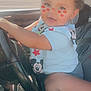 baby, bodypart, car, clothing, cosmetics, driving, face, finger, hand, head, lipstick, machine, person, photography, portrait, sitting, t_shirt, transportation, vehicle, wheel