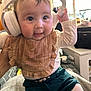 baby, headphones, bib, indoor, child, cute, clothing, person, smiling, sitting, infant, face, hand, expression, young, cozy, home, curious, apparel, candid