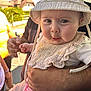 Maïley a rejoint le concours — aidez-le/la à gagner de superbes lots ! baby, infant, child, hat, bib, facial_expression, funny_face, adult_hand, arm, outdoor, daylight, person, clothing, holding, skin, cute, expression, portrait, people, background