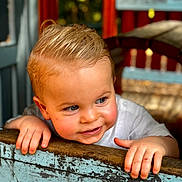 Louca participe au concours pour gagner de l'argent avec cette photo : baby, blonde_hair, casual_clothing, child, curious, cute, face, greenery, hands, happy, nature, outdoor, playful, portrait, red_paint, smiling, sunlight, toddler, weathered_wood, wooden_fence