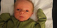 Jace is registered to the contest to win money with this photo: baby, infant, child, towel, green_clothing, nike_logo, face, eyes, hands, lying_down, portrait, indoor, fabric, zipper, head, skin, person, newborn, expression, cute