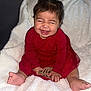 Esmeralda is registered to the contest to win money with this photo: baby, child, smiling, red_dress, bow, happy, infant, blanket, cute, sitting, feet, hands, portrait, indoors, soft_texture, playful, young, person, toddler, joy