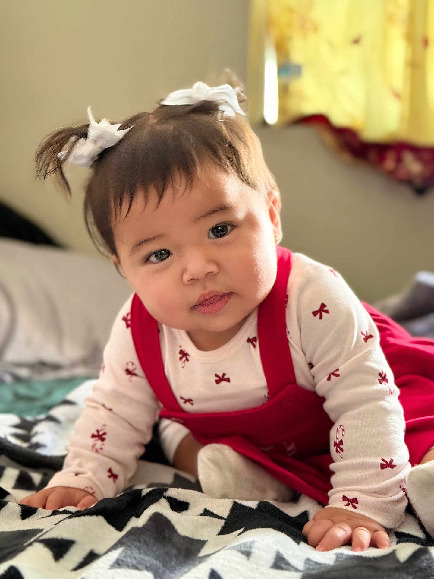 Esmeralda joined the competition — help win amazing prizes! baby, child, pigtails, bows, red_dress, white_shirt, patterned_blanket, crawling, indoors, curious_expression, chubby_cheeks, natural_light, window, soft_focus, cute, infant, face, hands, cozy, bedroom