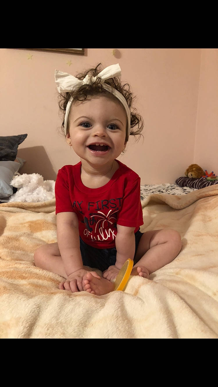 Mckenzie is registered to the contest to win money with this photo: baby, baby_toddler_clothing, child, comfort, dress, flash_photography, flooring, fun, goggles, happy, human_leg, joy, linens, person, photograph, pink, sitting, skin, sleeve, smile