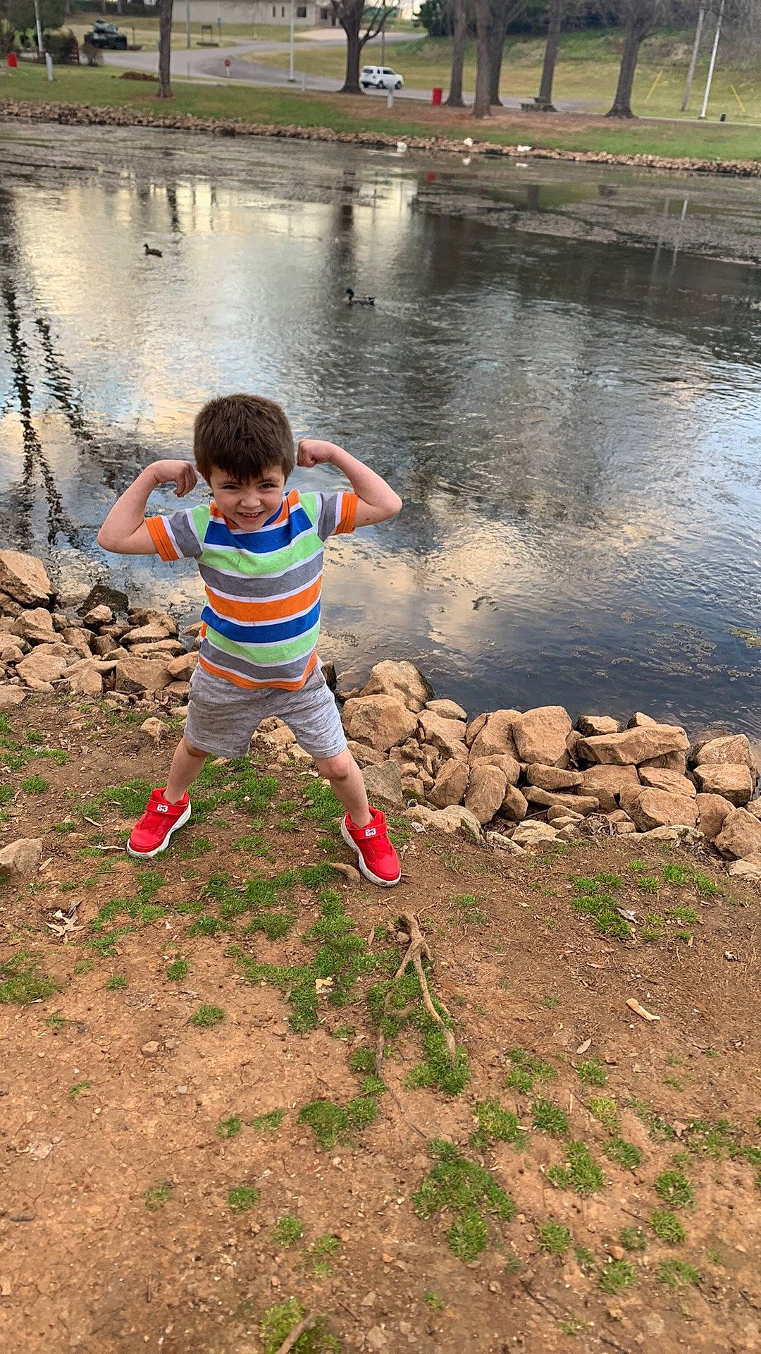Zaxdon is registered to the contest to win money with this photo: bank, child, fun, grass, happy, joy, lake, landscape, leg, leisure, people_in_nature, person, plant, recreation, reservoir, soil, t_shirt, toddler, tree, water
