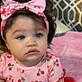child, baby, toddler, girl, curly_hair, blue_eyes, pink_headband, bow, pink_clothing, cherry_pattern, dress, portrait, indoor, blanket, sitting, closeup, eyelashes, expression, soft_lighting, cute