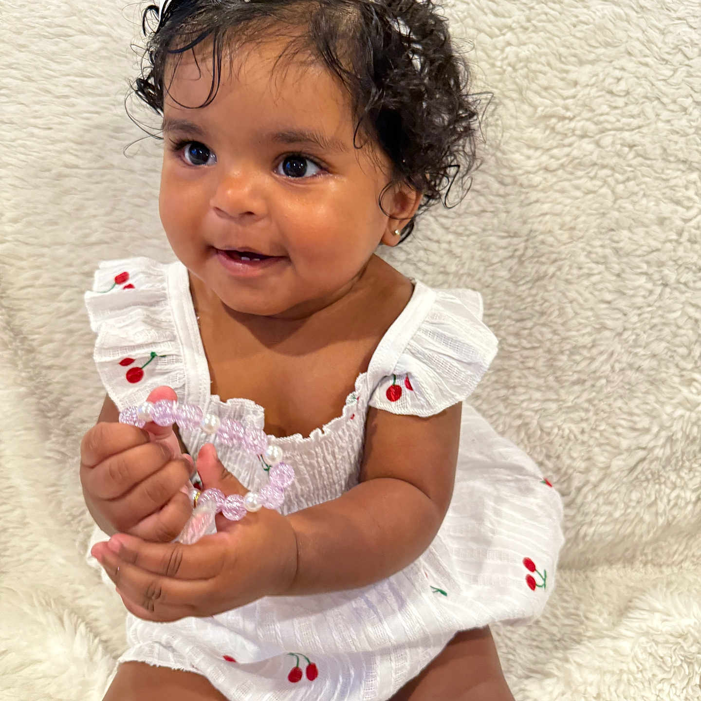 Mackenzie joined the competition — help win amazing prizes! adorable, baby, beads, bracelet, cherry_pattern, child, closeup, curly_hair, cute, fluffy_blanket, happy, indoors, infant, person, portrait, sitting, skin, smiling, white_bow, white_dress
