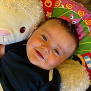 Kamryn joined the competition — help win amazing prizes! baby, smiling, infant, stuffed_animal, plush_toy, colorful_mat, child, cute, happy, face, indoor, soft_toy, black_shirt, play_mat, young_child, cuddling, portrait, lying_down, close_up, baby_boy