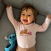 Luna Mouchet a rejoint le concours — aidez-le/la à gagner de superbes lots ! baby, child, smiling, happy, couch, plush_toy, stitch, blue, pink_clothing, raised_arms, indoor, cute, face, person, joyful, portrait, sitting, toy, infant, clothing