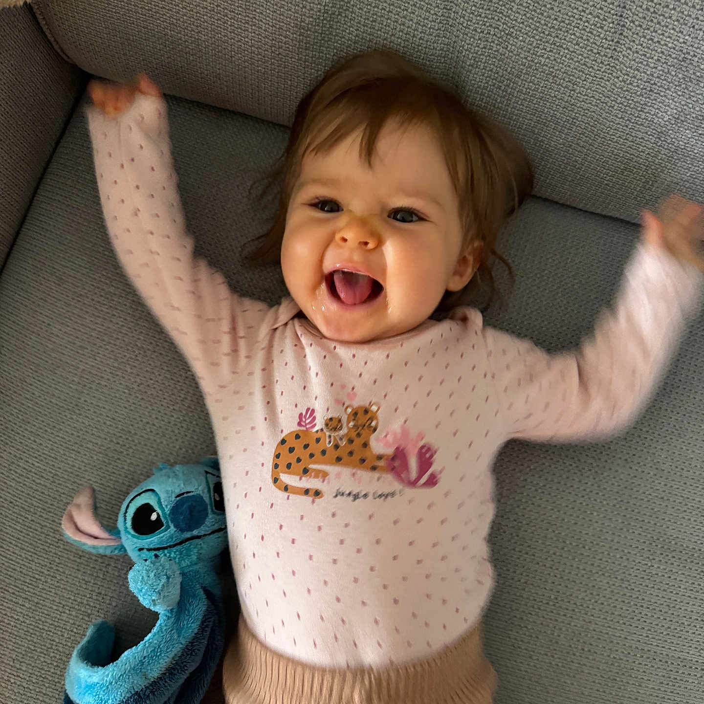 Luna Mouchet a rejoint le concours — aidez-le/la à gagner de superbes lots ! baby, blue, child, clothing, couch, cute, face, happy, indoor, infant, joyful, person, pink_clothing, plush_toy, portrait, raised_arms, sitting, smiling, stitch, toy