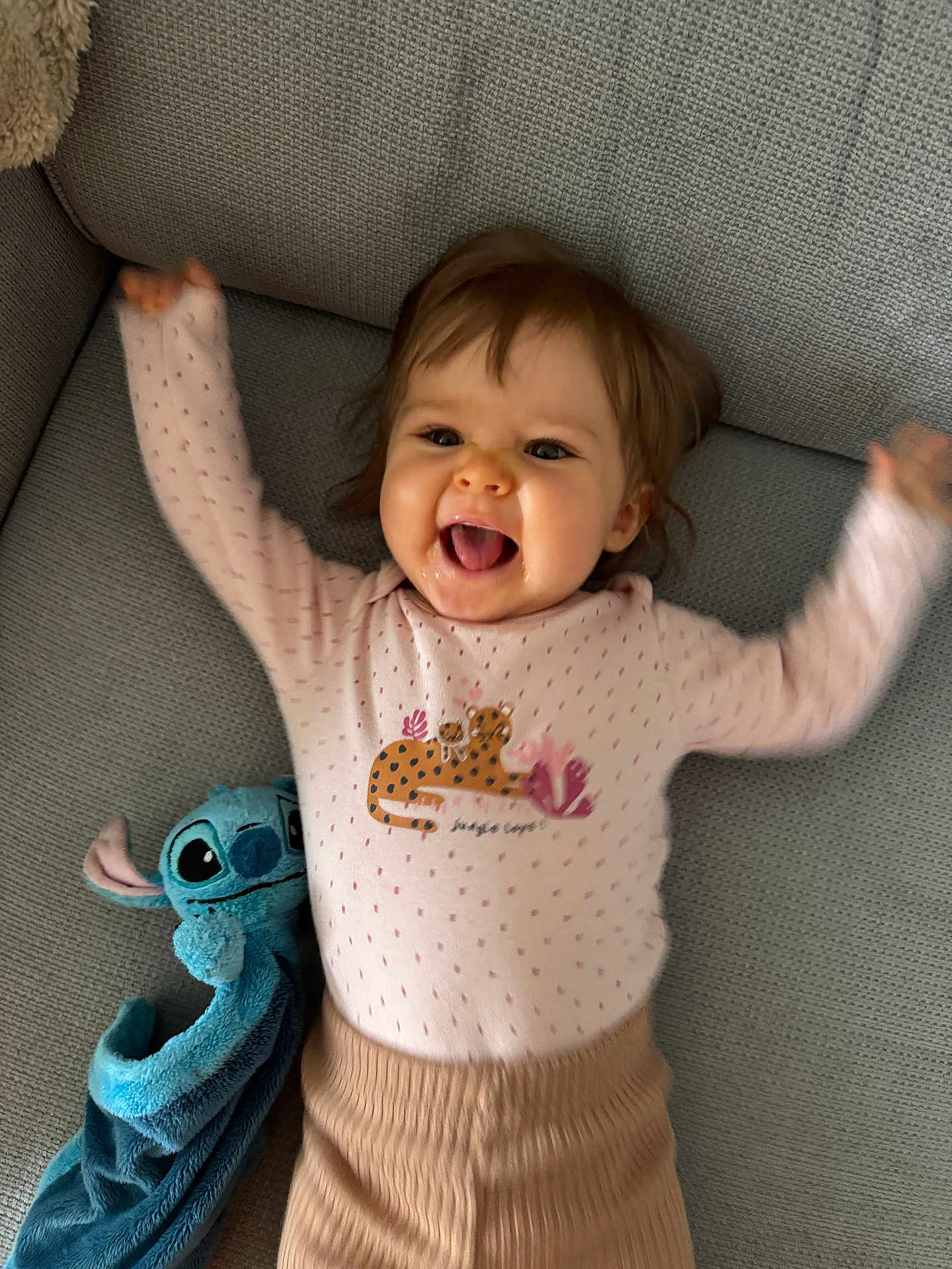 Luna Mouchet a rejoint le concours — aidez-le/la à gagner de superbes lots ! baby, child, smiling, happy, couch, plush_toy, stitch, blue, pink_clothing, raised_arms, indoor, cute, face, person, joyful, portrait, sitting, toy, infant, clothing
