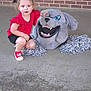 Gracee is registered to the contest to win money with this photo: child, girl, red_shirt, black_shorts, red_shoes, bow, mascot_head, pom_poms, concrete_floor, brick_wall, crouching, cheerleader, face, blue_eyes, toy, costume, outdoor, expression, person, cute