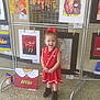 Gracee joined the competition — help win amazing prizes! child, girl, red_dress, red_bow, black_boots, art_display, paintings, floor, smiling, indoor, exhibition, portrait, young_child, clothing, person, happy, standing, gallery, colorful, decor