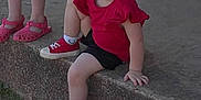 Gracee joined the competition — help win amazing prizes! child, girl, toddler, smiling, red_clothing, red_shoes, bow, outdoor, concrete, sidewalk, brick_wall, person, casual, happy, shorts, sitting, footwear, playful, daylight, two_children