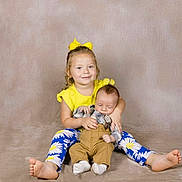 Gracee is registered to the contest to win money with this photo: baby, baby_clothes, barefoot, blue_leggings, child, cute, family, floral_pattern, happy, holding, indoor, infant, neutral_background, people, portrait, sibling, smiling, studio_photo, toddler, yellow_clothing