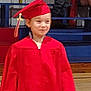 Leslie joined the competition — help win amazing prizes! child, graduation, red_gown, red_cap, gymnasium, bleachers, person, young, smile, celebration, event, indoors, floor, wooden_floor, tassel, audience, seated, clothing, portrait, happy