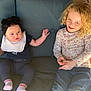 baby, child, toddler, couch, cushion, headband, bow, curly_hair, jeans, long_sleeve, floral_pattern, socks, smile, sitting, indoor, window, glass, furniture, person, portrait