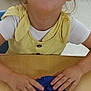 child, girl, yellow_dress, white_shirt, playdough, blue_playdough, red_cookie_cutter, table, classroom, smiling, happy, hands, face, indoor, furniture, brown_hair, kid, learning, playing, preschool