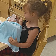 Journey joined the competition — help win amazing prizes! child, doll, toy_kitchen, bottle, blanket, chair, indoor, play, feeding, ponytail, wooden_furniture, young_child, pretend_play, kitchen_sink, toy_stove, table, floor, clothing, hair_tie, playroom