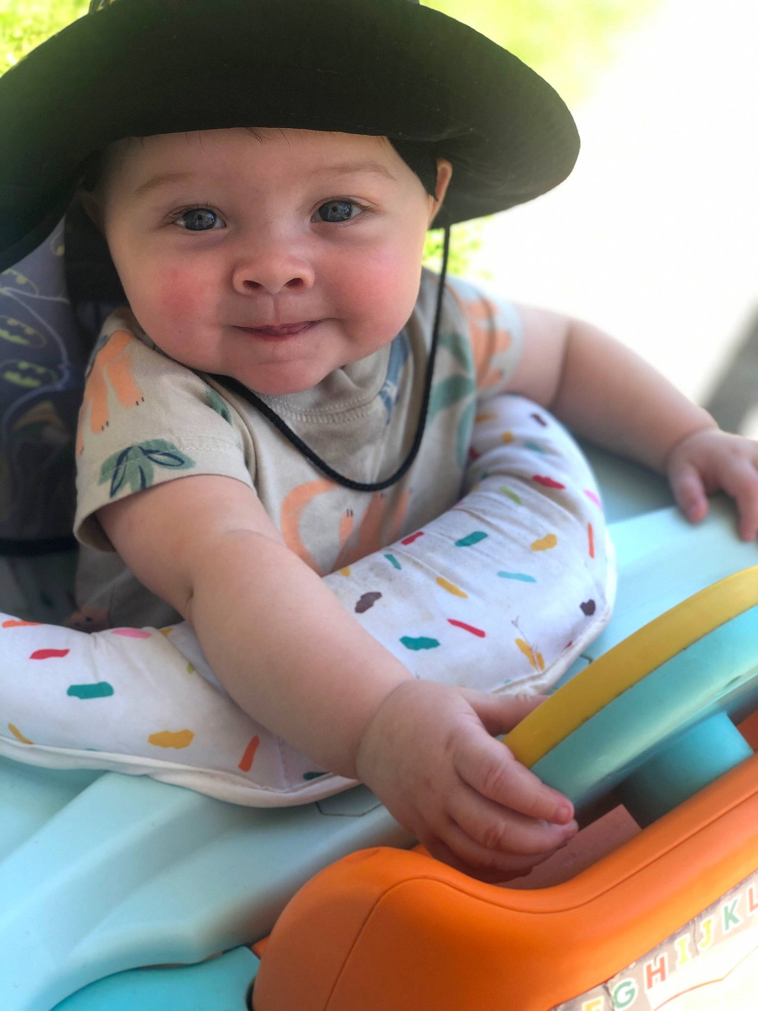 Brantley is registered to the contest to win money with this photo: baby, baby_toddler_clothing, cap, child, face, facial_expression, fedora, finger, grass, hairstyle, happy, hat, headwear, joy, leisure, person, photograph, product, riding_toy, skin