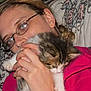 person, glasses, kitten, cat, cuddle, hand, face, fur, indoor, pattern, fabric, closeup, cozy, comfort, portrait, animal, pet, young, cute, casual