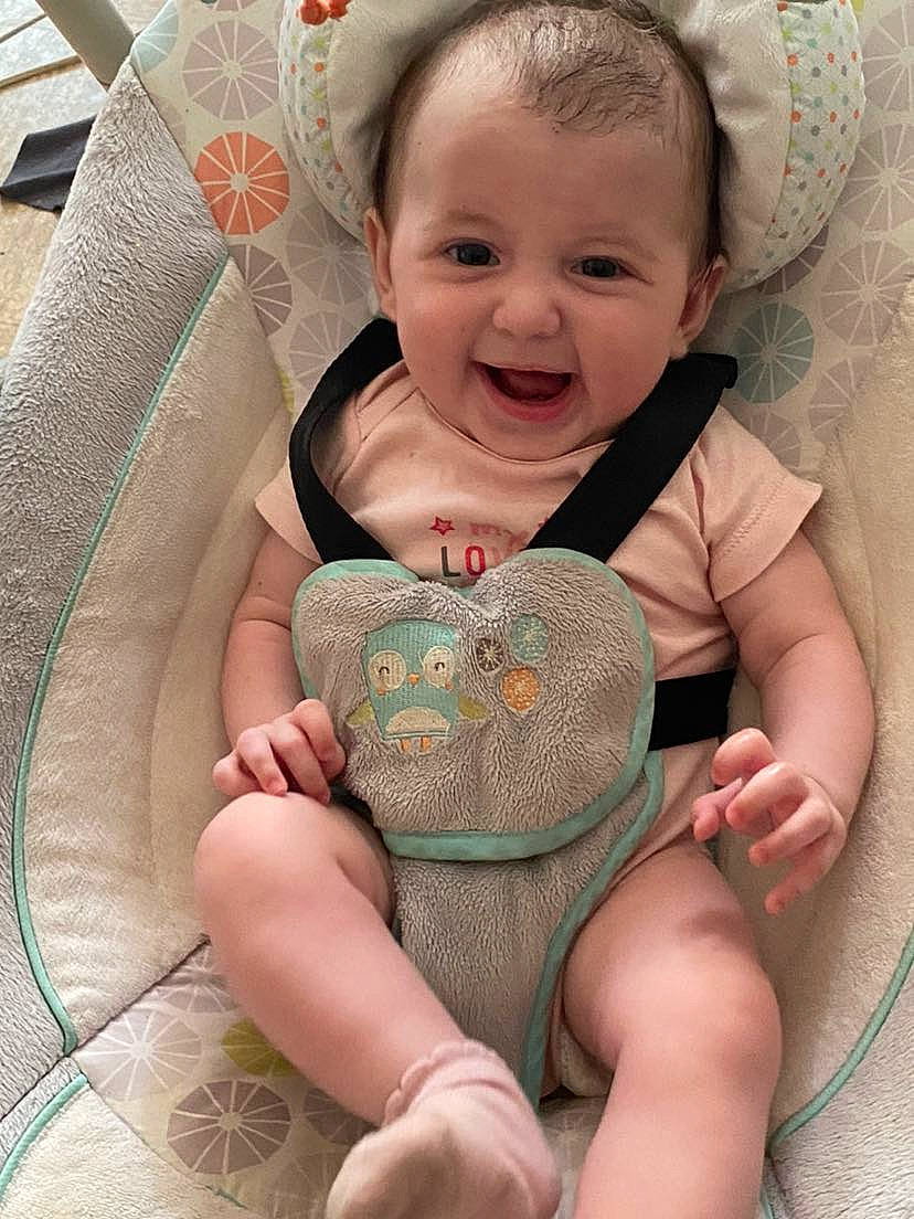 Myla participe au concours pour gagner de l'argent avec cette photo : baby, baby_toddler_clothing, cheek, child, comfort, eye, face, facial_expression, happy, head, joy, linens, pattern, person, pink, sitting, skin, smile, stomach, textile