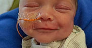 Olivia joined the competition — help win amazing prizes! newborn, baby, infant, sleeping, smiling, face, portrait, medical_tube, feeding_tube, hospital, blanket, blue_blanket, cream_clothing, onesie, close_up, indoors, head, hand, cozy, healthcare