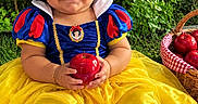 Zara Isabella joined the competition — help win amazing prizes! baby, child, toddler, portrait, smiling, happy, snow_white_costume, red_bow, blue_dress, yellow_skirt, apple, fruit_basket, outdoor, garden, greenery, grass, storybook, princess, sitting, family_friendly