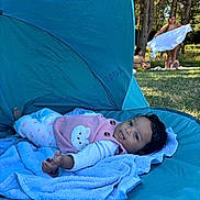 Eliya a rejoint le concours — aidez-le/la à gagner de superbes lots ! baby, toddler, towel, blue_tent, outdoor, grass, people, trees, sunlight, relaxing, park, child, clothing, pink, purple, smile, face, nature, summer, playful