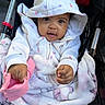 baby, child, infant, stroller, portrait, smiling, happy, sunhat, blanket, hooded_clothing, floral_pattern, pink, white, sitting, outdoor, cozy, face, hands, baby_clothing, photography