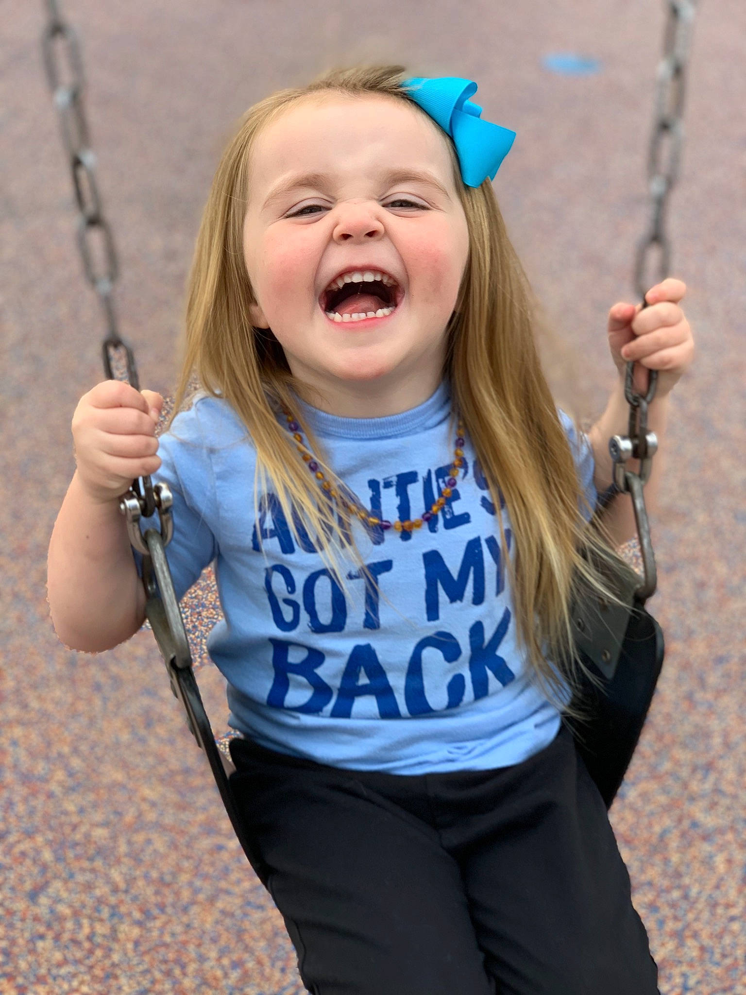 Kimberlynn is registered to the contest to win money with this photo: blue, child, clothing, face, facial_expression, finger, gesture, hair, hairstyle, hand, happy, human_body, outdoor_play_equipment, person, playground, recreation, sleeve, standing, swing, t_shirt