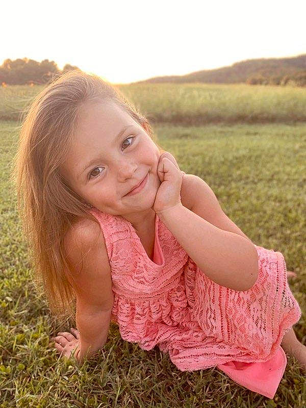 Sophia is registered to the contest to win money with this photo: arm, beauty, blond, child, child_model, eye, facial_expression, grass, grass_family, hair, happy, joy, long_hair, nose, people_in_nature, person, photograph, pink, sitting, skin